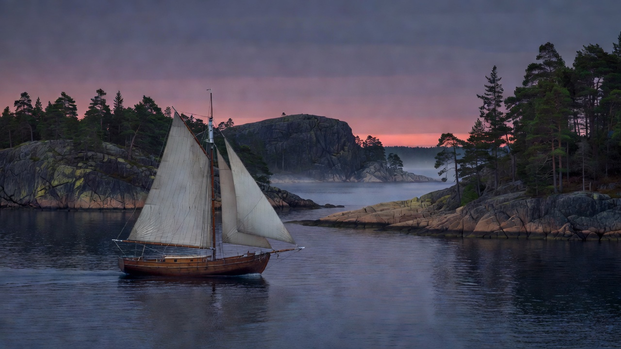 Classic sailing boat gliding past rocky granite islands and evergreen coastline at dusk